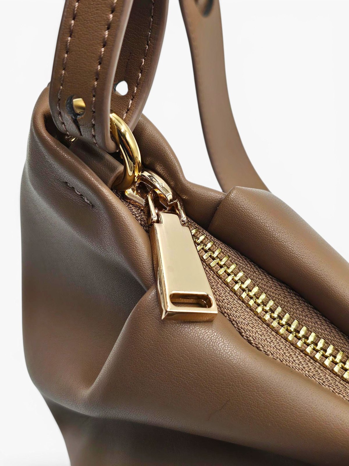 Close-up of The.Chai's gold-coloured top zip and pull